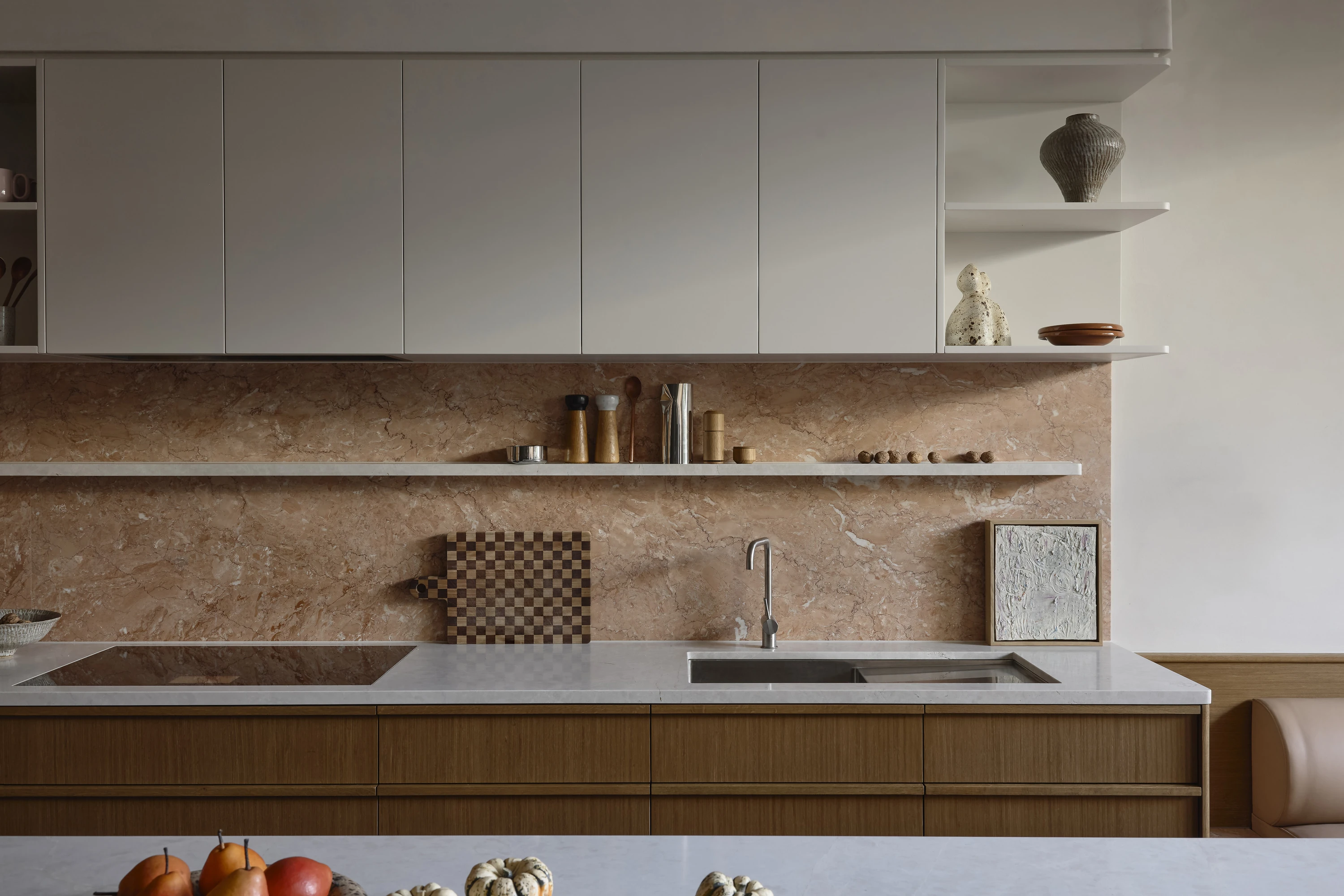 Oak kitchen with white upper cabinets and a pink marble splashback