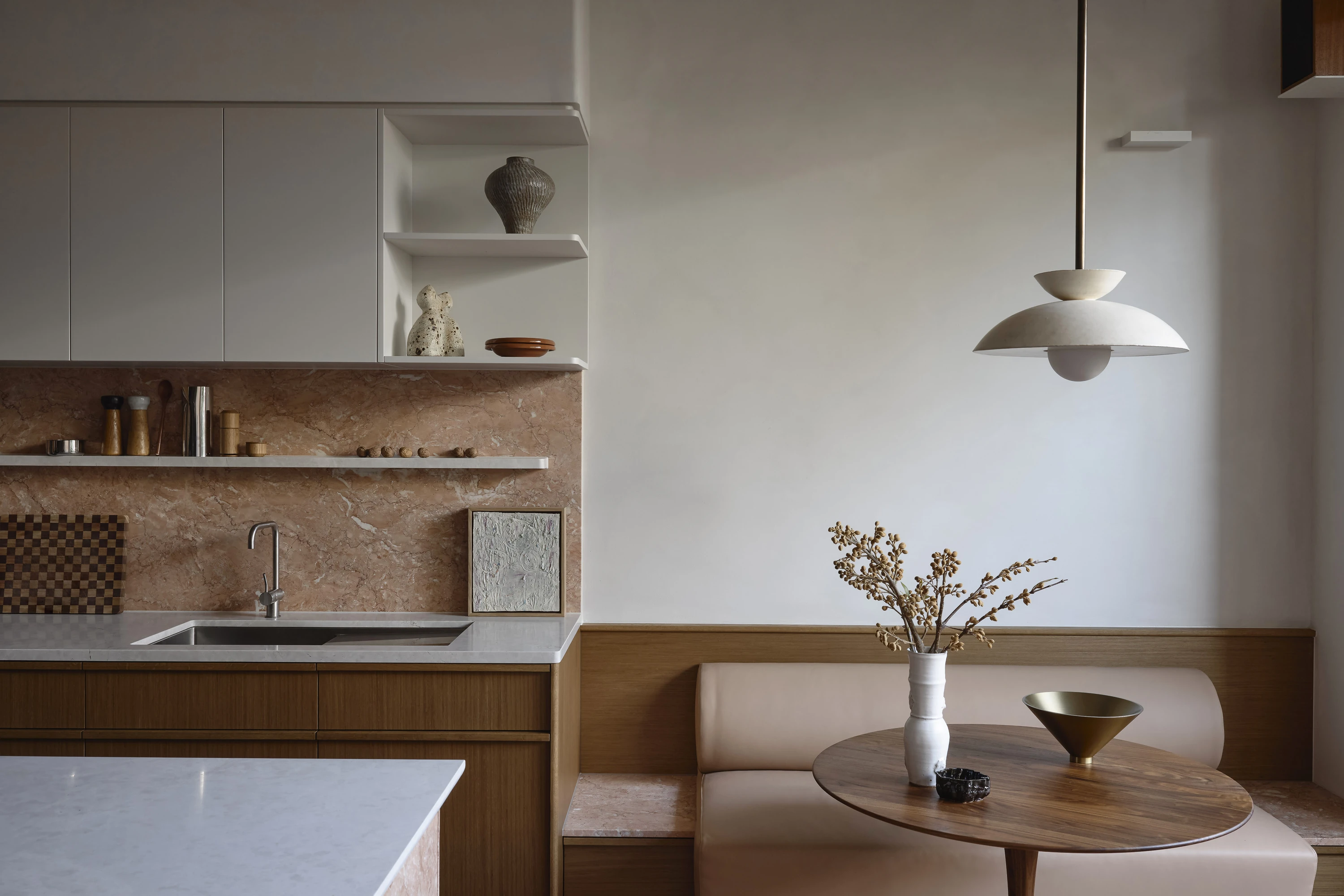 Oak kitchen with a pink marble splashback, opening onto a leather banquette