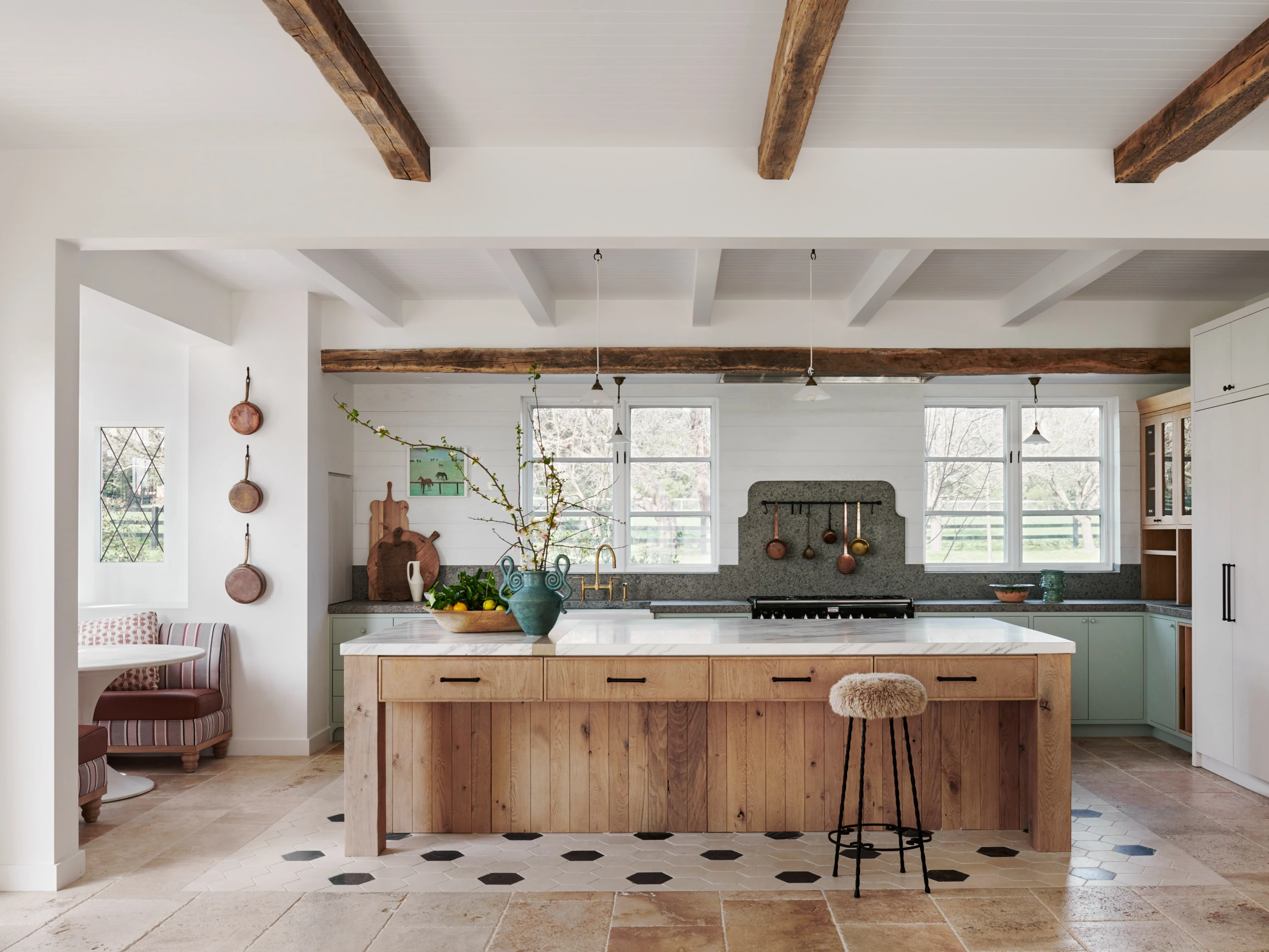 Farmhouse kitchen with a timber-clad island, marble top and pale green cabinetry